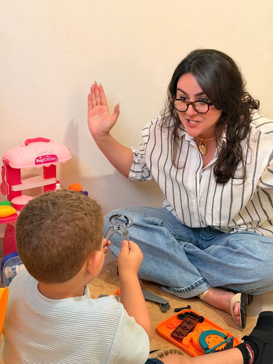 Fonoaudióloga em sessão lúdica com criança, usando brinquedos